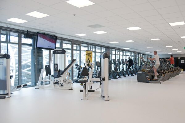 Moderne fitnessruimte aan de Prinses Beatrixlaan met cardio- en krachtapparatuur en sporters in actie.